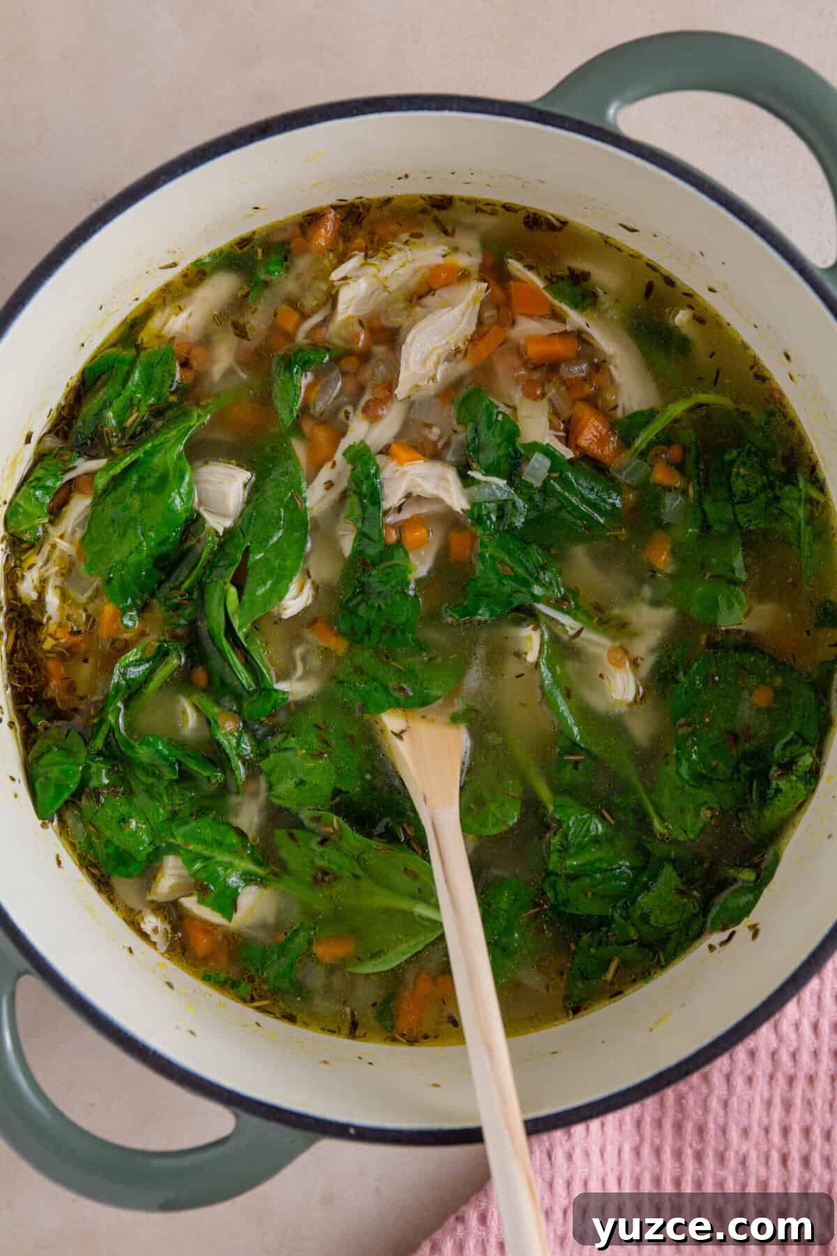 Hearty Chicken and Lentil Soup Recipe for Cozy Weeknights 8 A process shot of chicken and lentil soup making showing the chicken, lentils and spinach added to finish the soup.