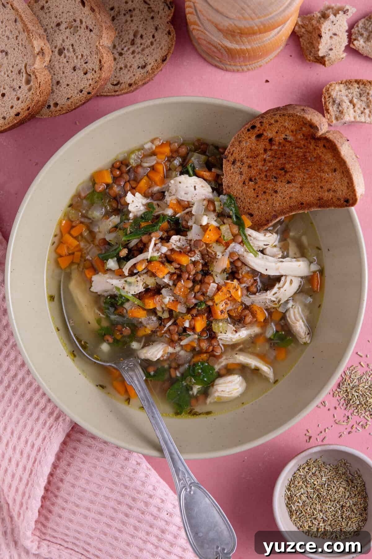 Hearty Chicken and Lentil Soup Recipe for Cozy Weeknights 9 A bowl of chicken and lentil soup with a slice of brown gluten free bread dipped in the side.
