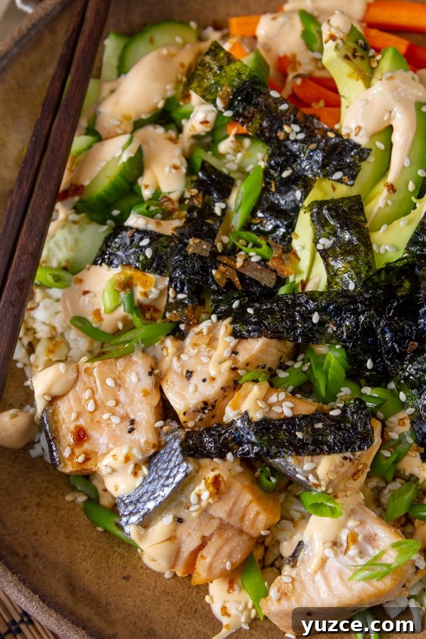 Grilled Salmon Bowl with Quinoa, Avocado & Citrus Dressing 4 Sushi bowl with salmon, avocado, vegetables, nori, sesame seeds, with chopsticks on the side.
