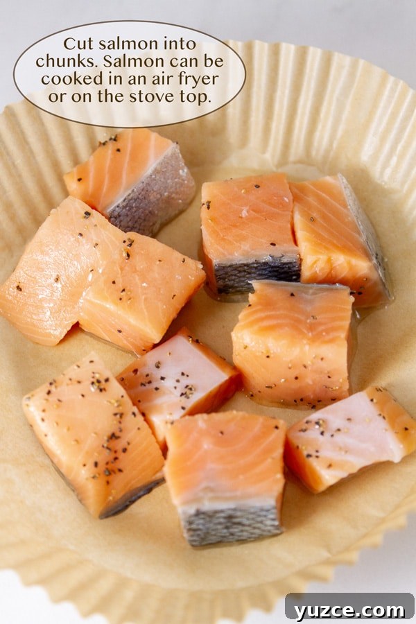 Grilled Salmon Bowl with Quinoa, Avocado & Citrus Dressing 7 raw salmon cut into small cubes seasoned with pepper in a parchment paper air fryer liner.