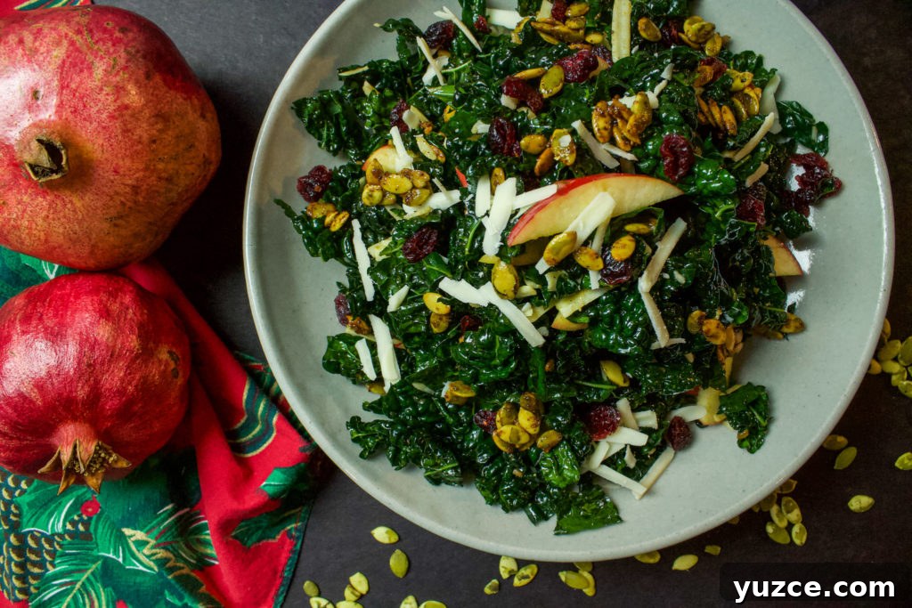 Winter Kale Salad with Roasted Butternut & Cranberry Vinaigrette 2 kale salad with cheese, pumpkin seeds, cranberries, and apple next to pomegranates on the table