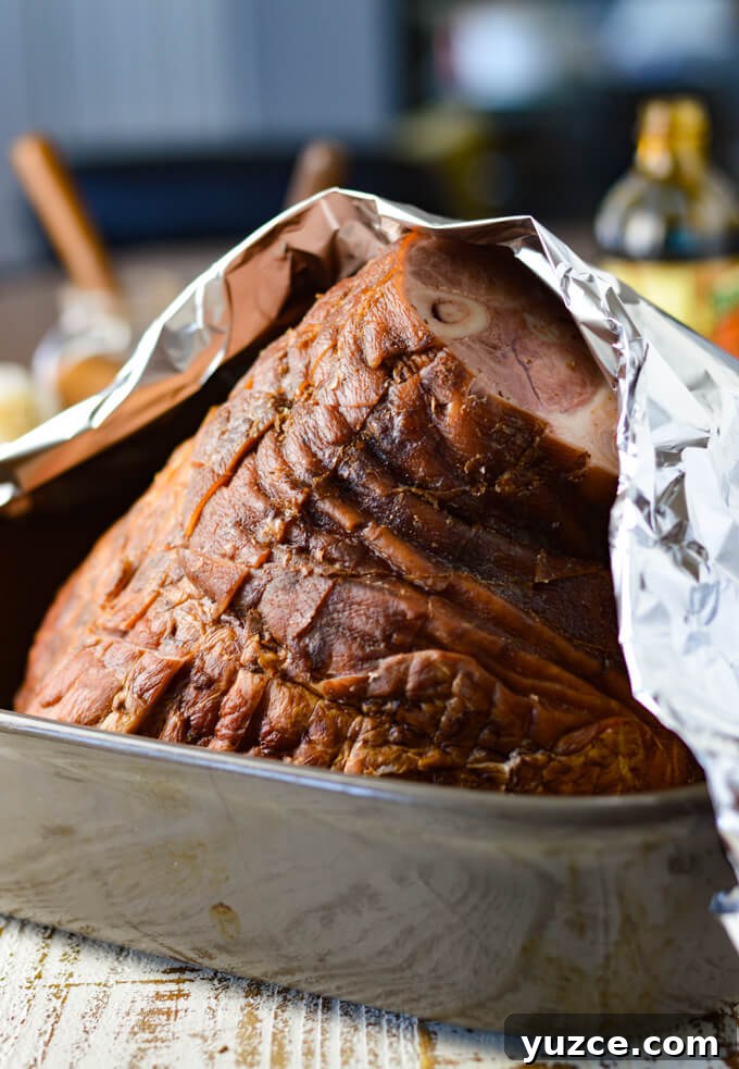 Brown Sugar and Whole Grain Mustard Glazed Baked Ham 4 A bone-in ham sitting in a shallow roasting pan with foil halfway over it. Ready to go in the oven.