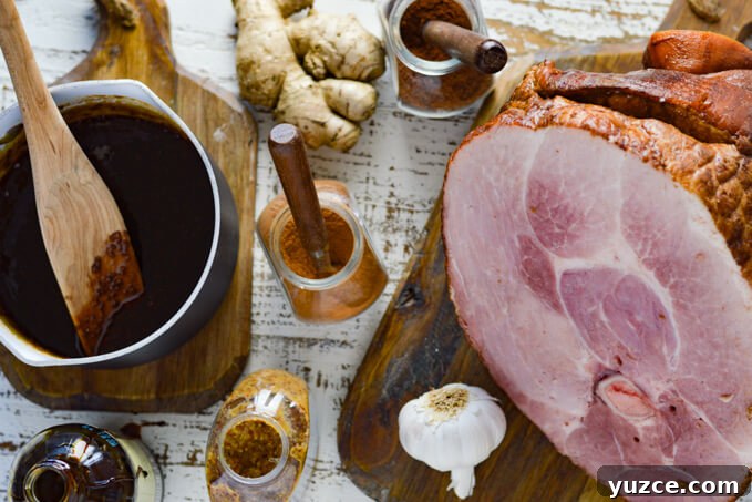 Brown Sugar and Whole Grain Mustard Glazed Baked Ham 5 A bone-in ham sits on a wooden board with garlic, fresh ginger, and spices and a pan of brown sugar glaze is on another wooden board.