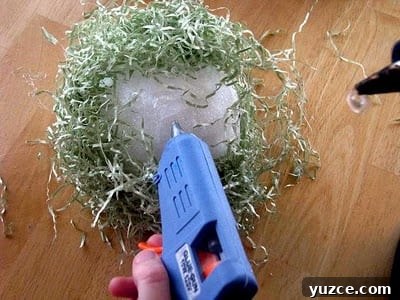 Spring Topiary Ideas to Refresh Your Garden Today 6 hand hot gluing craft grass onto styrofoam ball