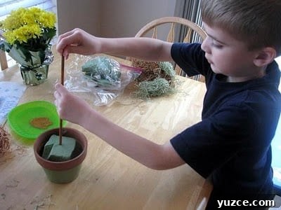 Spring Topiary Ideas to Refresh Your Garden Today 7 child placing dowel into floral foam