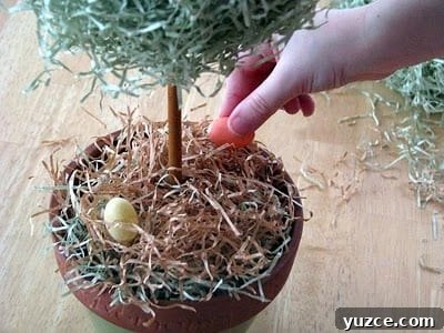 Spring Topiary Ideas to Refresh Your Garden Today 10 child adding small plastic eggs inside pot