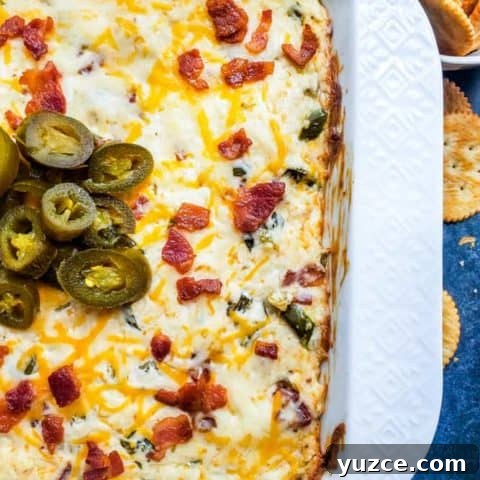 Overhead shot of jalapeno popper dip in white baking dish with crackers on side.