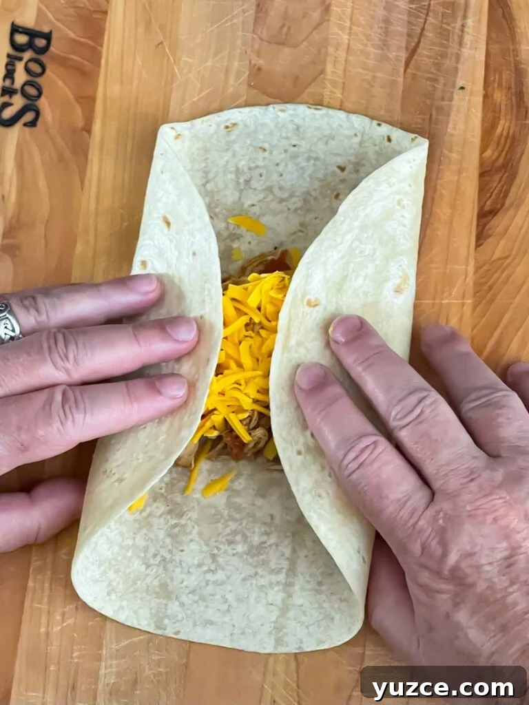 Crispy Baked Chicken Chimichangas with Cheesy Filling 6 Sides folded in on the tortilla on a wooden board.