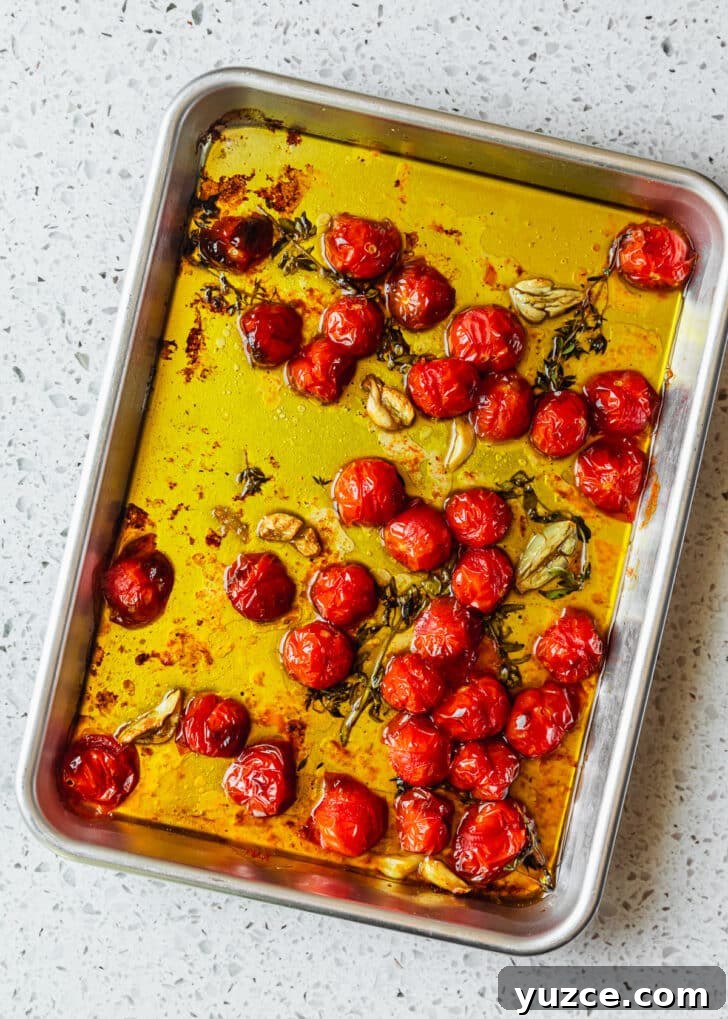 Baked Caprese Crostini with Fresh Basil Pesto 6 A silver sheet pan of roasted cherry tomatoes on a white counter.