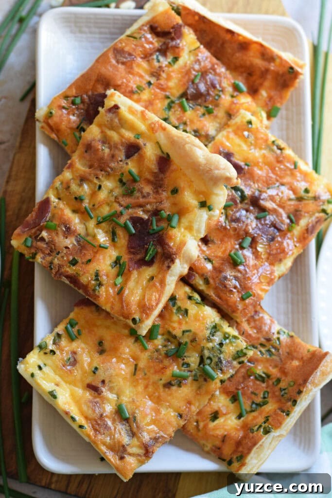 Flaky Puff Pastry Breakfast Quiche with Spinach and Cheese 15 Sheet pan breakfast quiche cut into squares on a plate.
