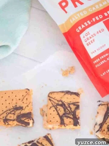 Frozen protein s'mores on parchment paper with a protein powder behind it.