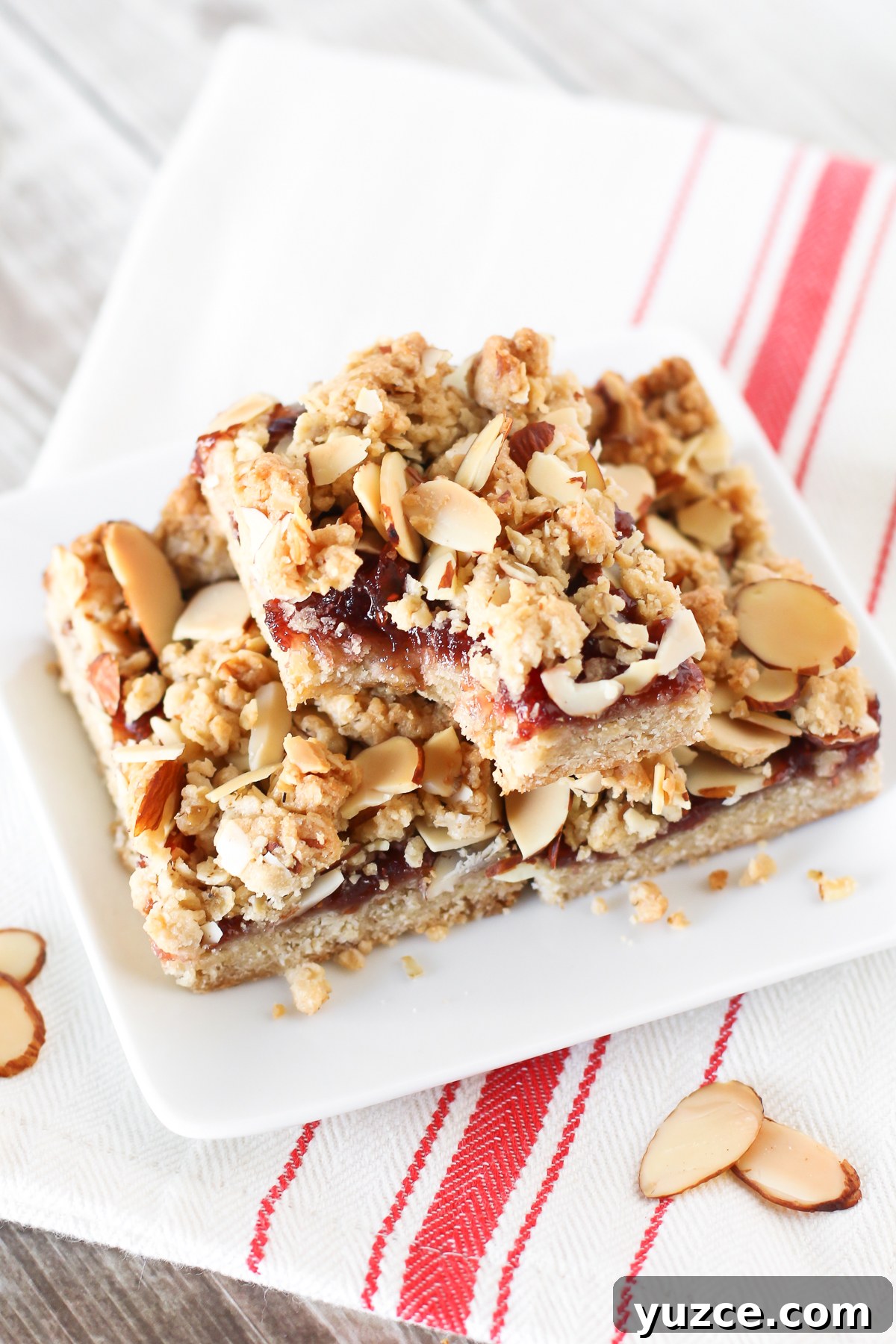 Gluten Free Vegan Raspberry Almond Crumb Bars. Layers of crumb topping, sweet raspberry jam and toasted almonds. The perfect bite!