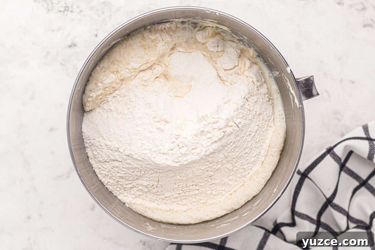 Elegant White Wedding Cake Ideas for Timeless Celebrations 9 adding dry ingredients to wet ingredients for white wedding cake batter in a stand mixer bowl.