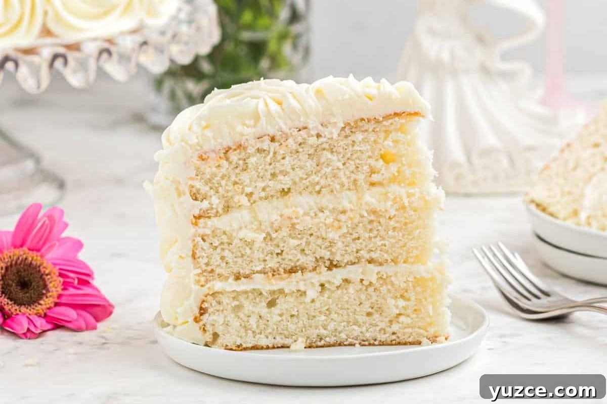 Elegant White Wedding Cake Ideas for Timeless Celebrations 3 side view of a slice of white wedding cake on a white plate showing its three layers.