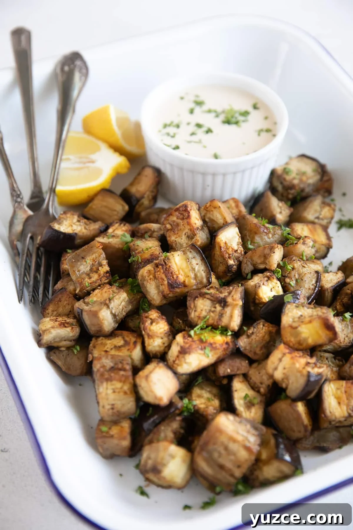 Crispy Oven-Roasted Eggplant with Garlic and Herbs 5 White tray filled with golden roasted eggplant garnished with chopped parsley.