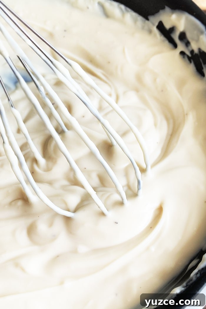 Creamy Garlic White Pizza Sauce Made in One Pot 2 Easy Garlic White Pizza Sauce in Black Pot With Whisk