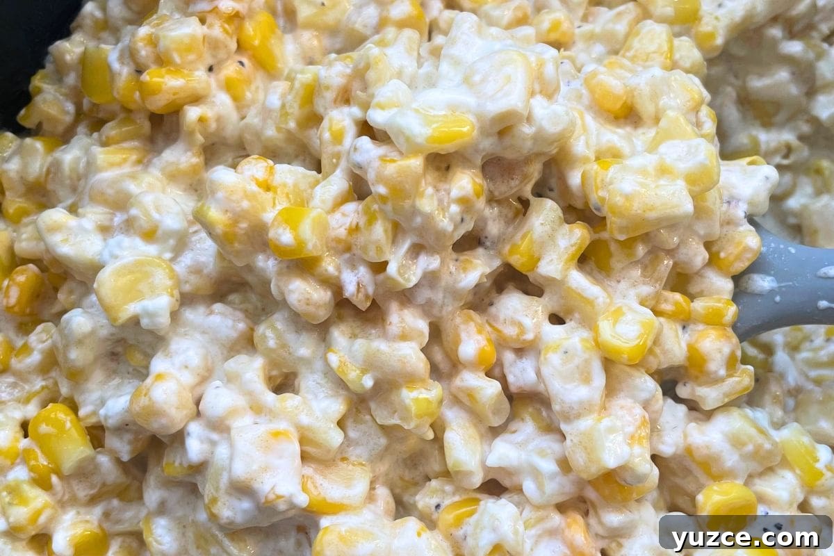 13 Crockpot Thanksgiving Recipes to Save Oven Space 2 Close-up image of a creamy corn casserole with visible kernels and a spoon.