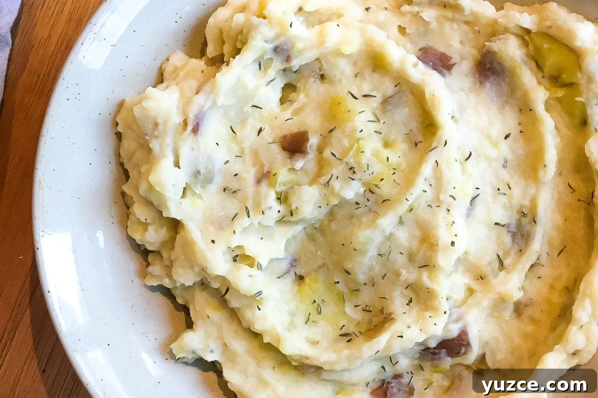 13 Crockpot Thanksgiving Recipes to Save Oven Space 14 A close-up of homemade mashed potatoes garnished with herbs on a white plate.