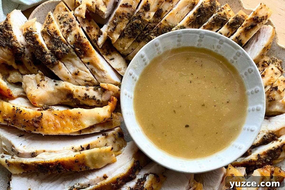 13 Crockpot Thanksgiving Recipes to Save Oven Space 3 Sliced herb-crusted turkey breast arranged on a plate next to a bowl of gravy.