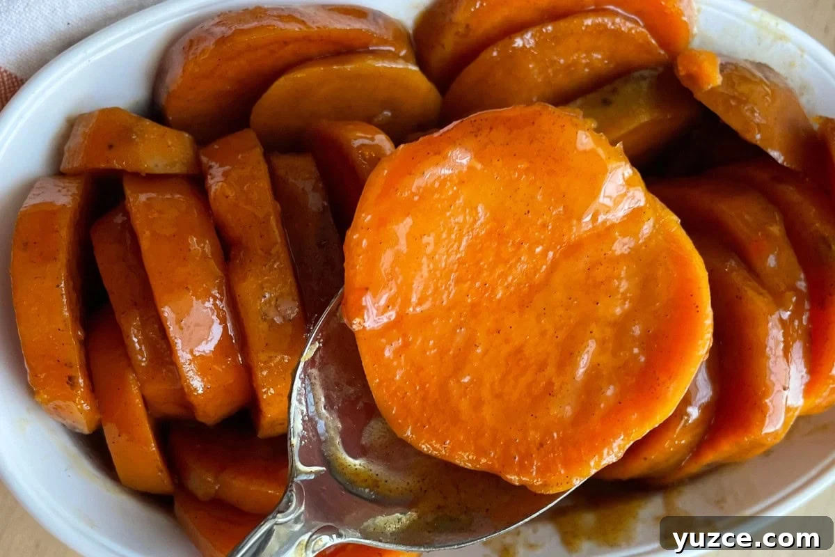 13 Crockpot Thanksgiving Recipes to Save Oven Space 9 A close-up of glazed candied sweet potatoes in a white dish.