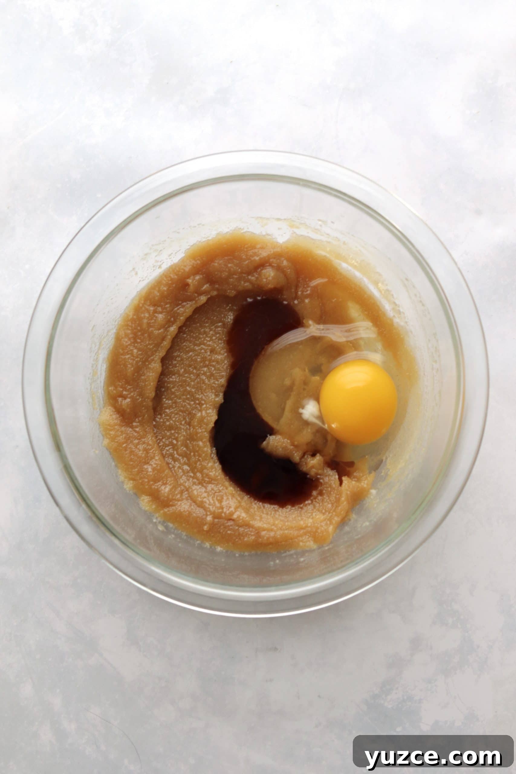 Egg being stirred into melted butter and brown sugar.
