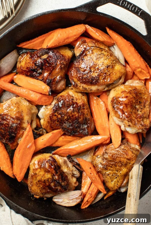 Perfectly Roasted Whole Chicken in a Cast Iron Skillet 11 Crispy bone in chicken thighs and carrots in a cast iron pan with a spatula after being seared.
