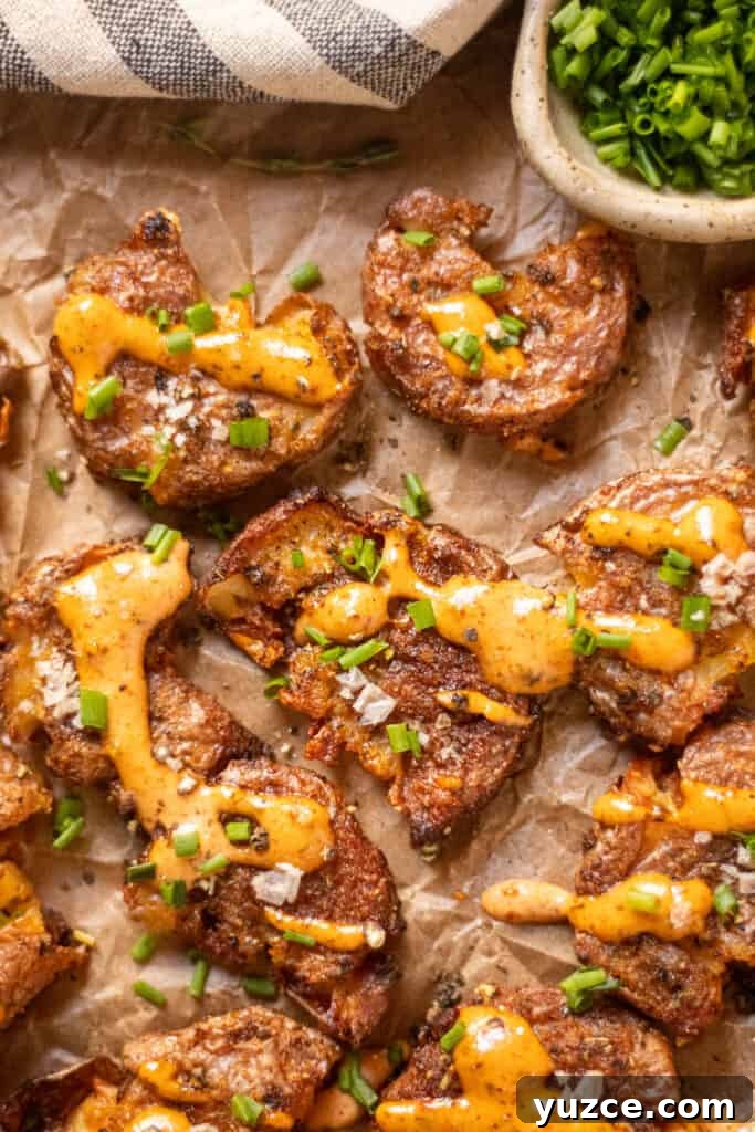 Crispy Smashed Potatoes with Spicy Creole Sauce 2 overhead shot of crispy smashed potatoes with creole sauce on parchment paper.