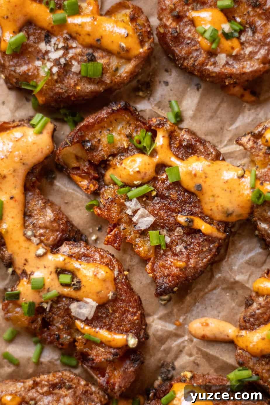 Crispy Smashed Potatoes with Spicy Creole Sauce 11 close up overhead shot of crispy smashed potatoes with creole sauce on parchment paper.