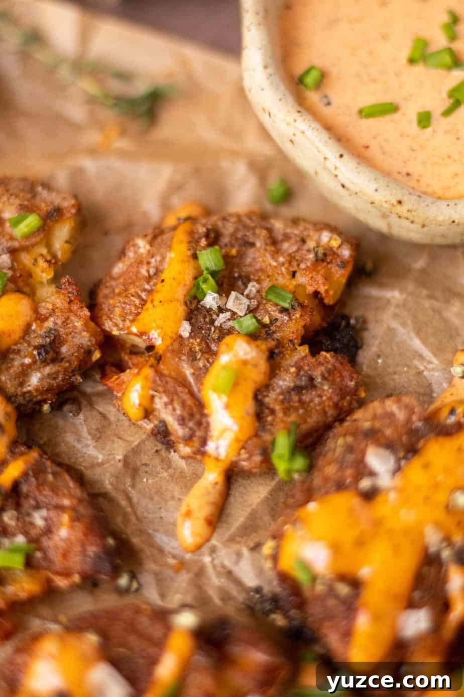 Crispy Smashed Potatoes with Spicy Creole Sauce 10 close up overhead shot of crispy smashed potatoes with creole sauce on parchment paper.