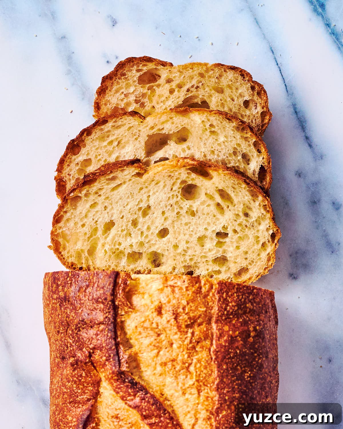 Crispy Air Fryer Crouton Recipe for Salad and Soup 12 Slices of a sourdough bread loaf on a marble counter.