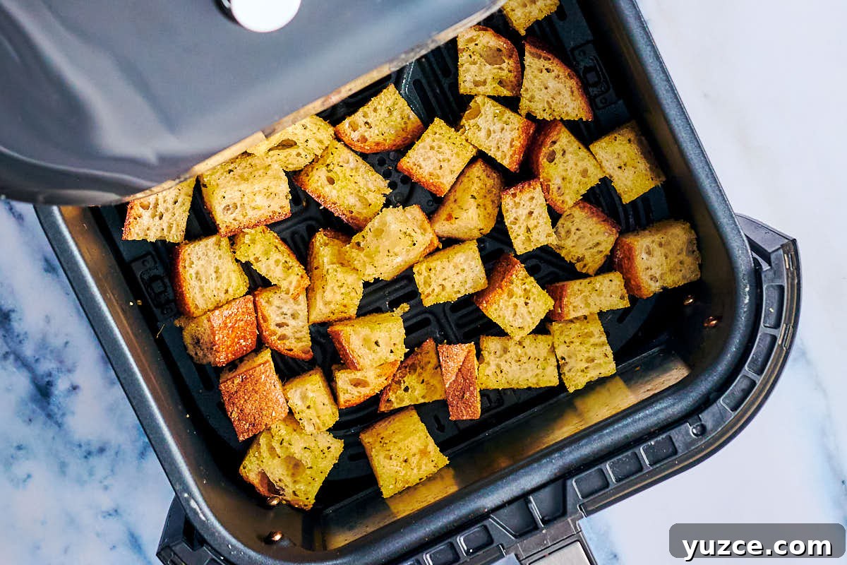 Crispy Air Fryer Crouton Recipe for Salad and Soup 8 Seasoned bread cubes in an air fryer basket before baking.