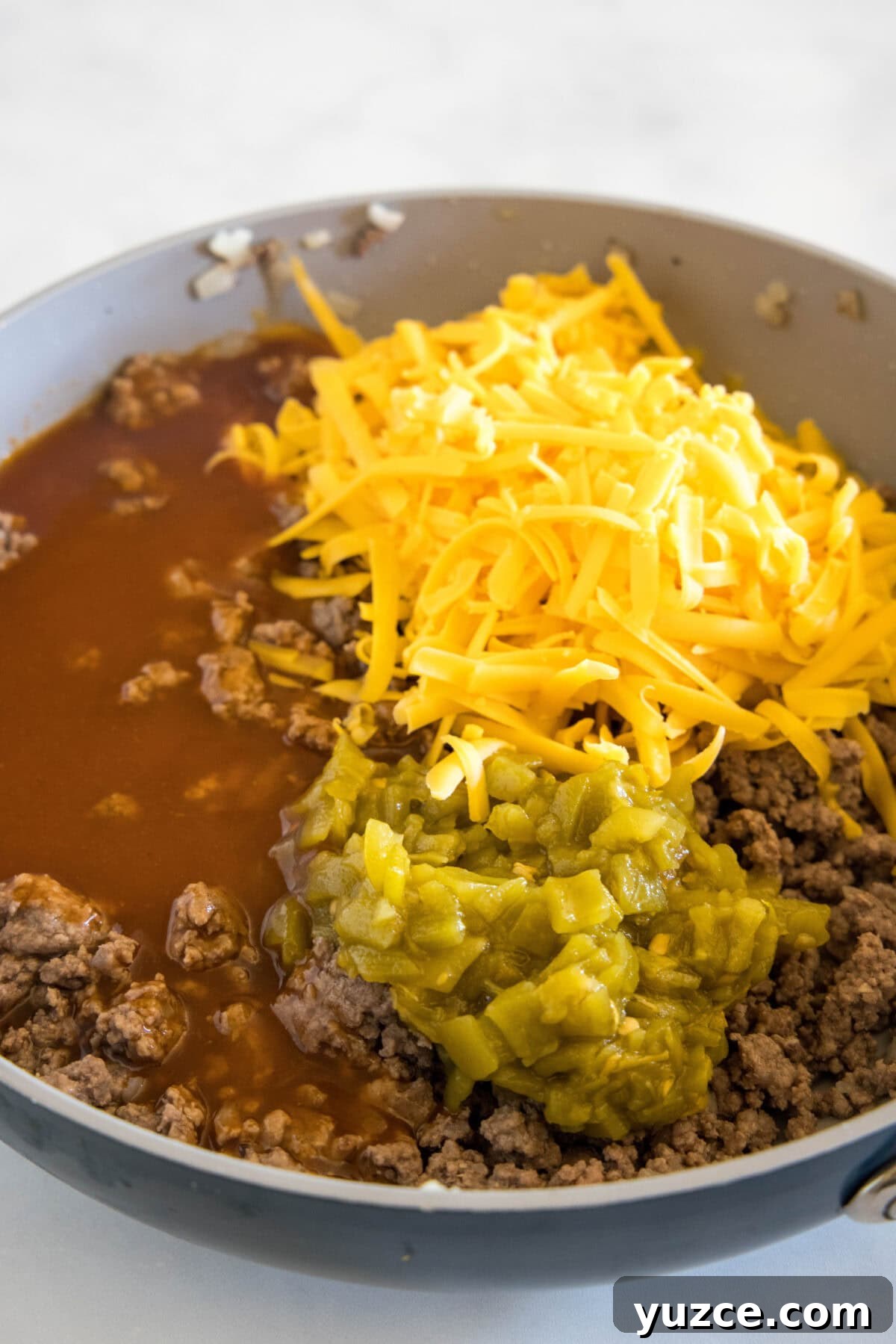 Loaded Beef Enchilada Dip Recipe for Party Appetizers 4 mixing ground beef, enchilada sauce, green chiles and cheddar cheese together