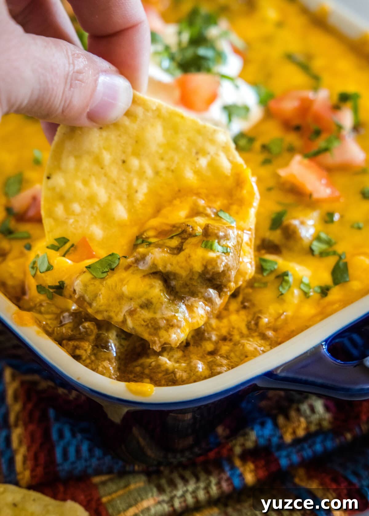 Loaded Beef Enchilada Dip Recipe for Party Appetizers 6 scooping enchilada dip out of baking dish with a tortilla chip