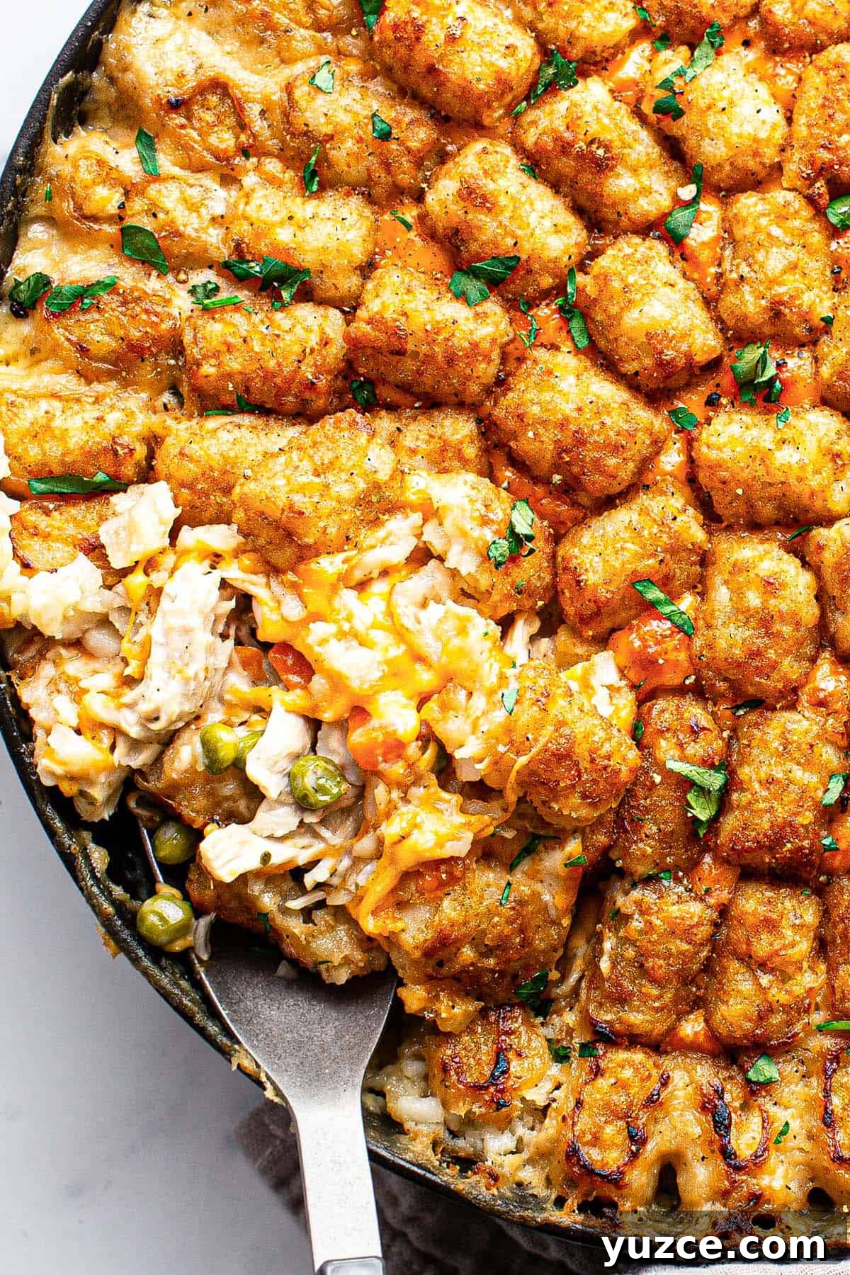 Close up of chicken tater tot casserole with a serving spoon in it. 