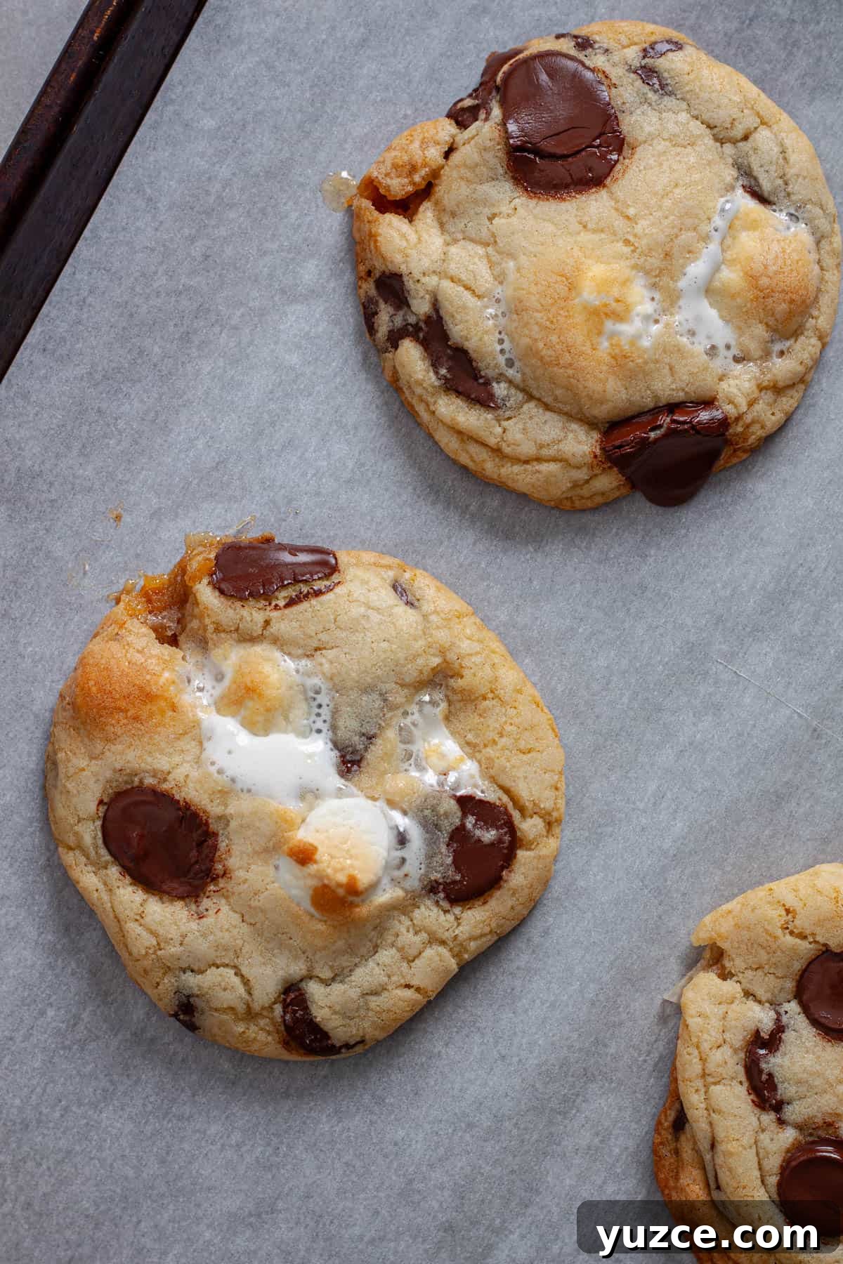 Chewy Chocolate Chip Cookies with Gooey Marshmallow Centers 15 Chocolate chip marshmallow cookies cooling on a parchment lined baking sheet.