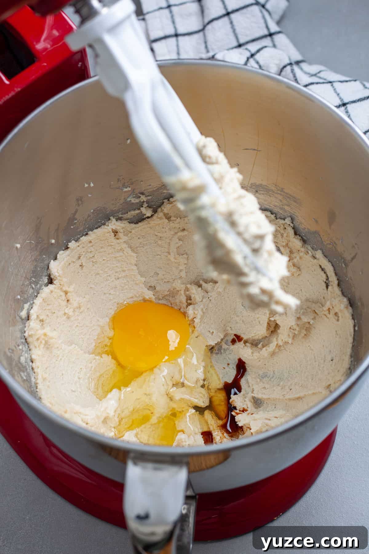 Chewy Chocolate Chip Cookies with Gooey Marshmallow Centers 7 An egg and vanilla extract added to a stand mixer bowl with whipped sugar and butter.