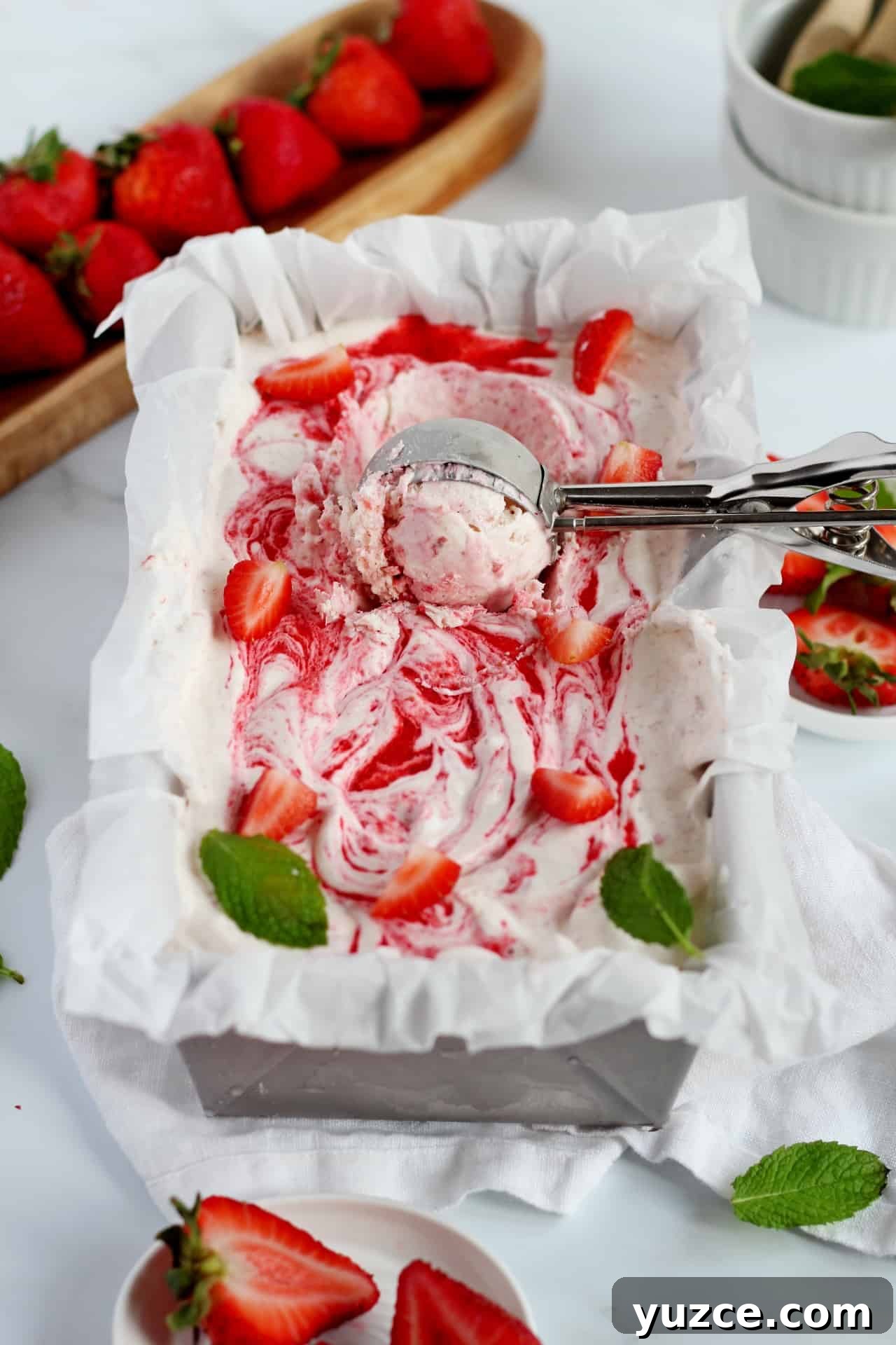 No-Churn Fresh Strawberry Ice Cream Recipe 2 strawberry ice cream in loaf pan with scoop spoon