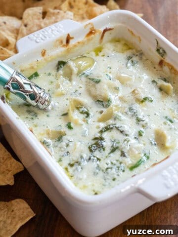 Spinach and artichoke dip in a dish with some tortilla chips next to it.