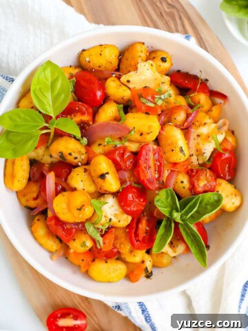 A bowl filled with gnocchi, vegetables, and basil.