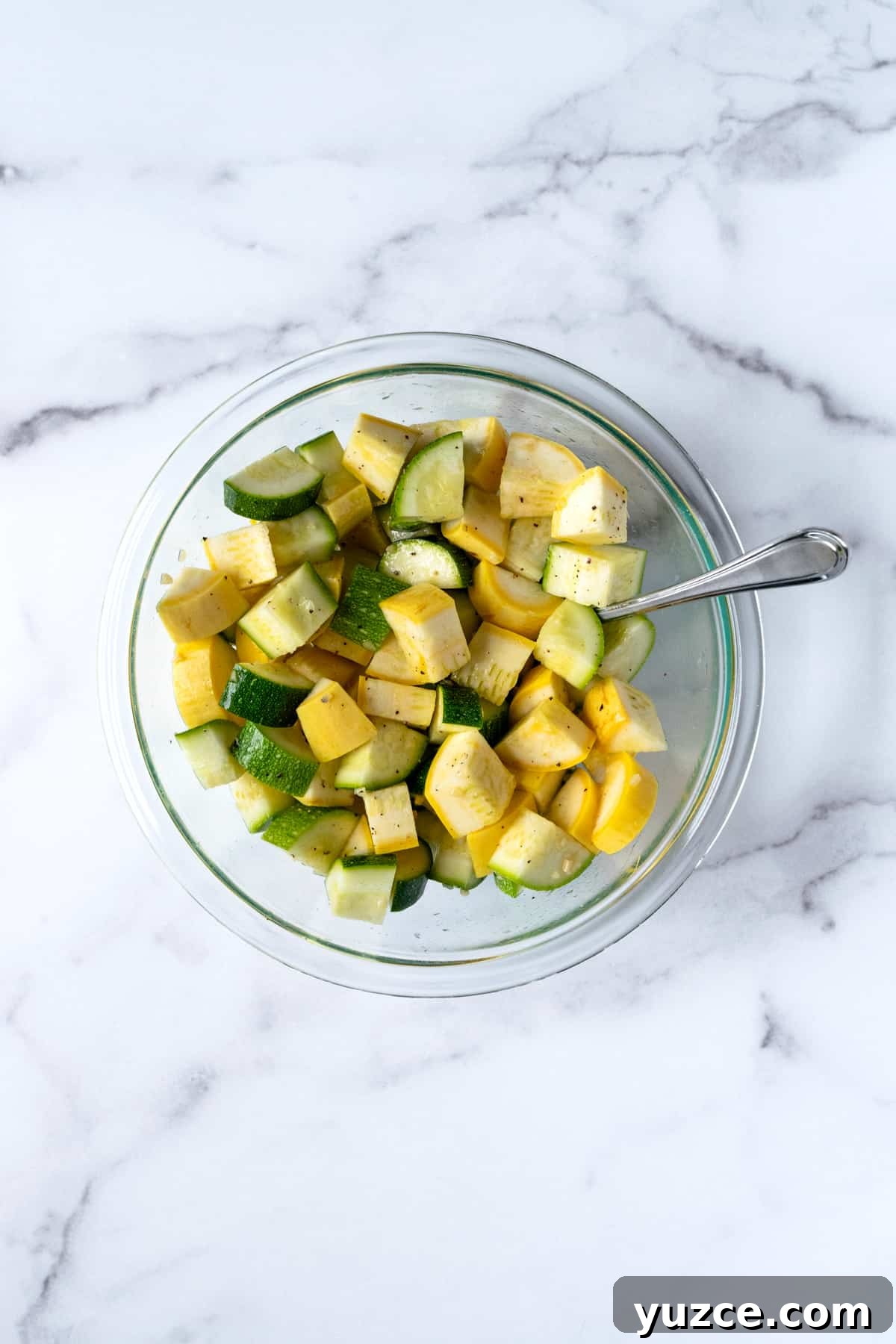 Crispy Air Fryer Zucchini & Summer Squash Recipe 5 Chopped Zucchini and Squash in a glass bowl with a spoon.