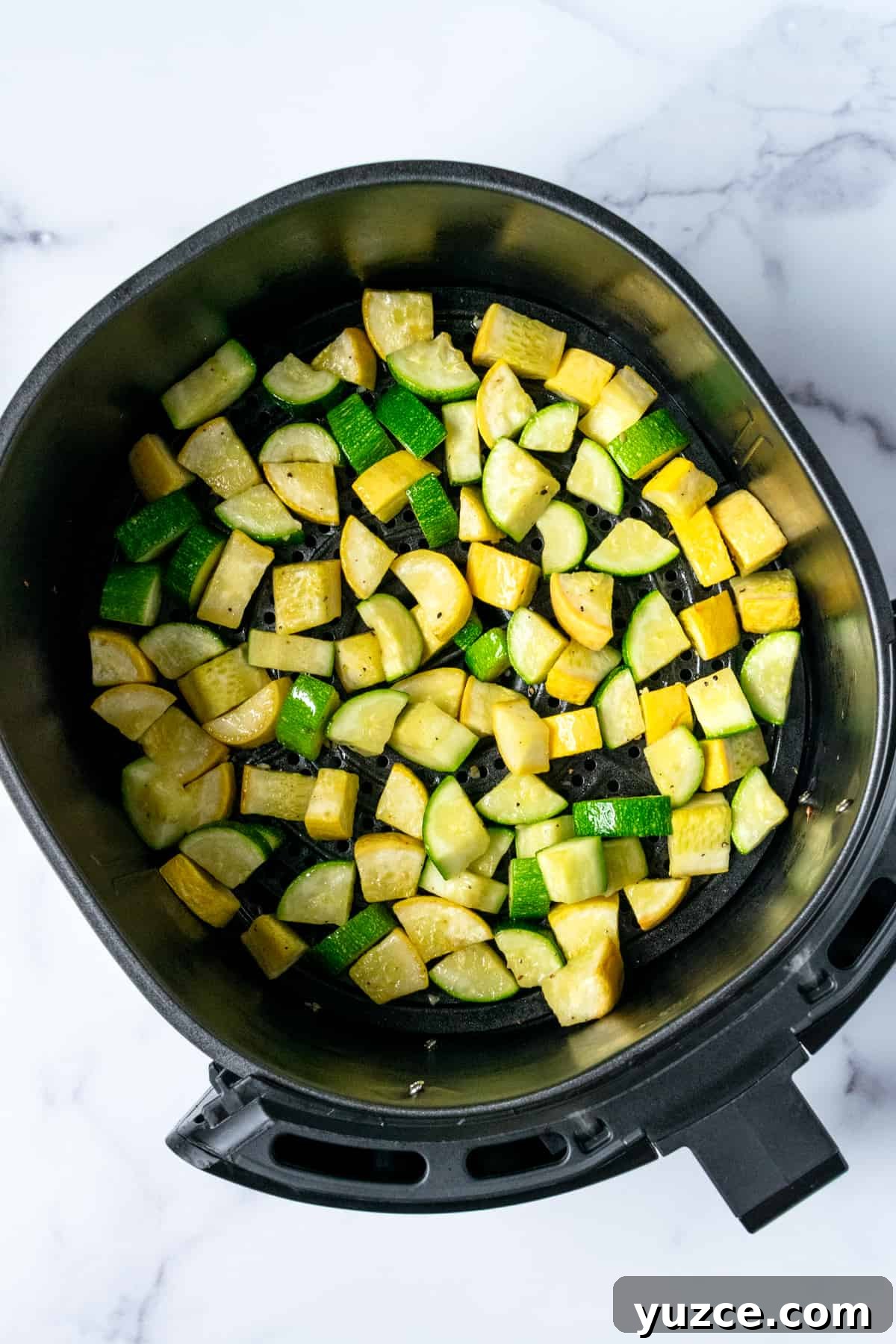 Crispy Air Fryer Zucchini & Summer Squash Recipe 6 Zucchini and Squash chunks in an air fryer basket.