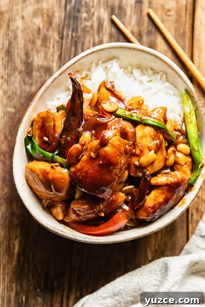 Sichuan Szechuan Chicken: Spicy Stir-Fry Recipe with Garlic Chili Oil 2 Top down shot of szechuan chicken with green onions and peppers on a bed of rice in a small bowl