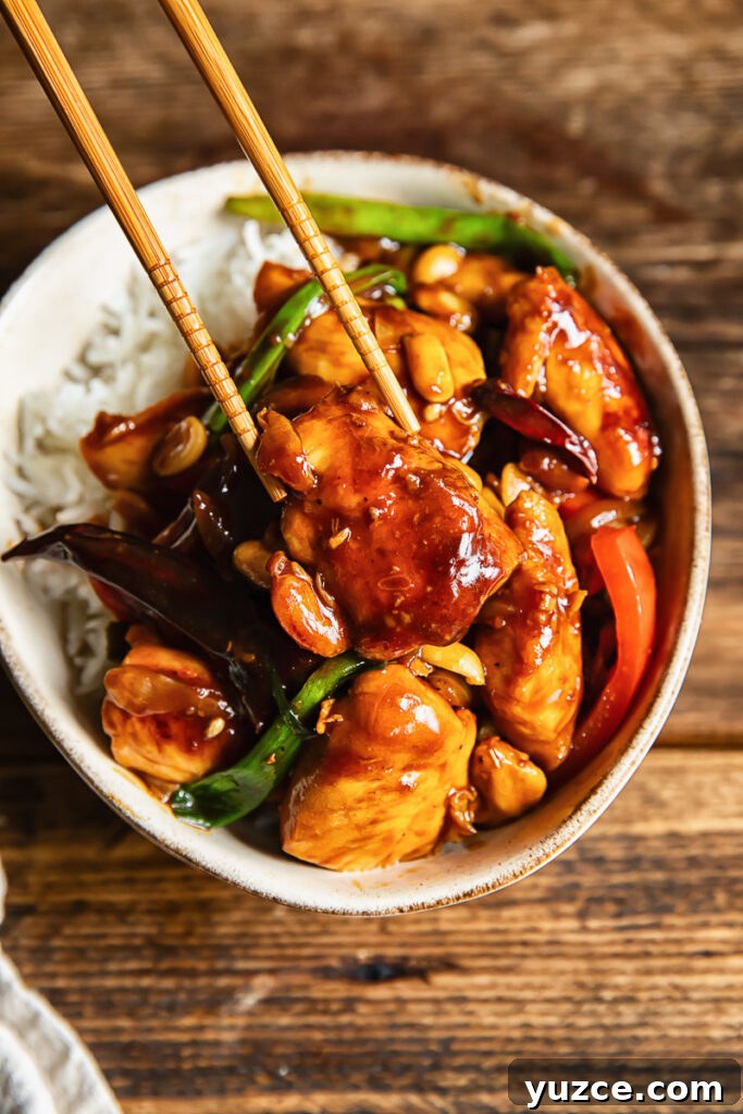 Sichuan Szechuan Chicken: Spicy Stir-Fry Recipe with Garlic Chili Oil 4 Close up shot of piece of chicken being picked up with chopsticks from szechuan stir fry