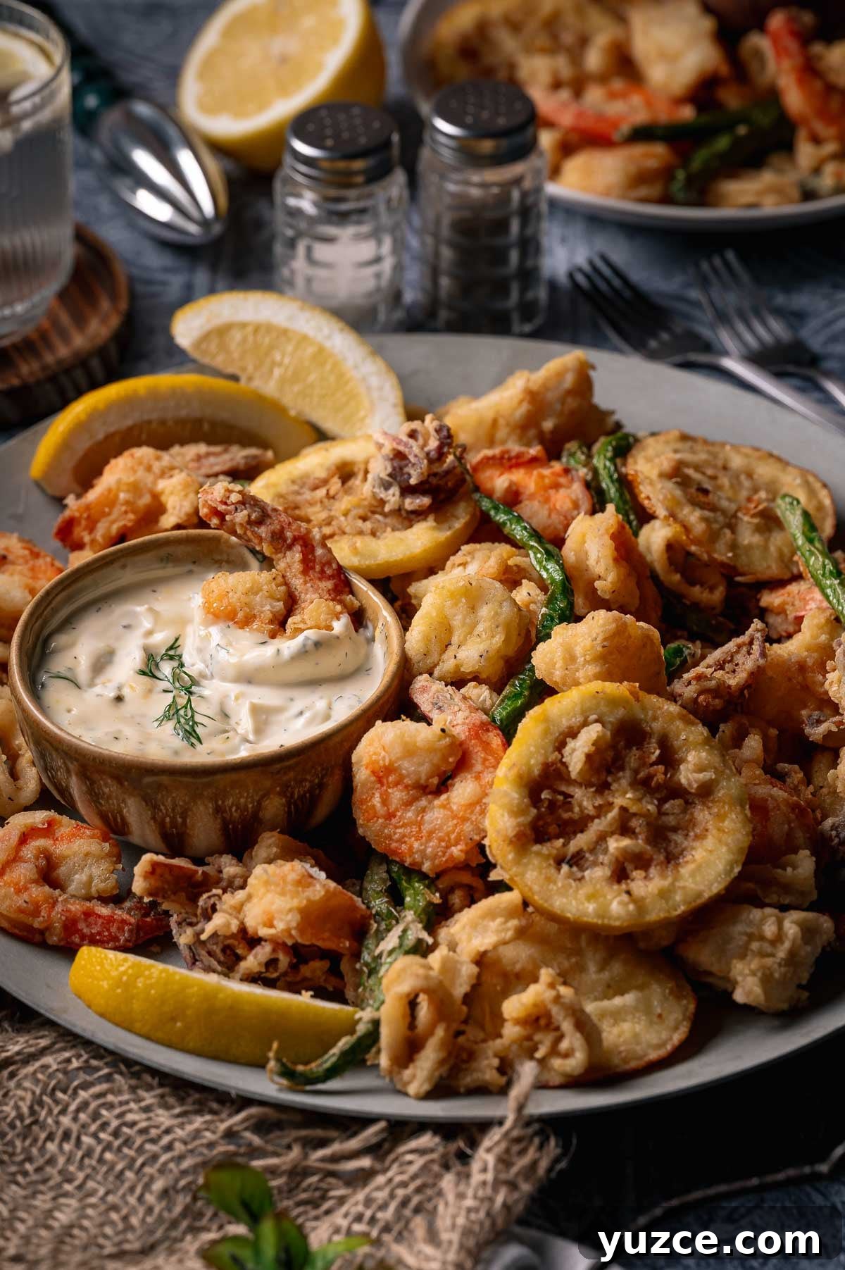Crispy Fritto Misto with Lemon-Dill Tartar Sauce 2 A plate of fritto misto; assorted fried seafood and vegetables with lemon wedges and a bowl of creamy dipping sauce, garnished with dill.