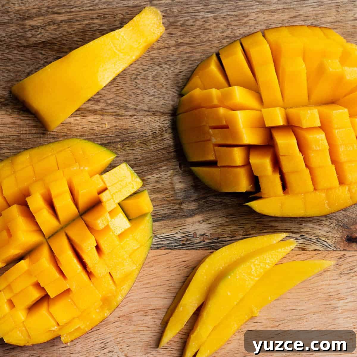 Two Large pieces of mango with a crosshatch and two smaller strips on a wooden board.