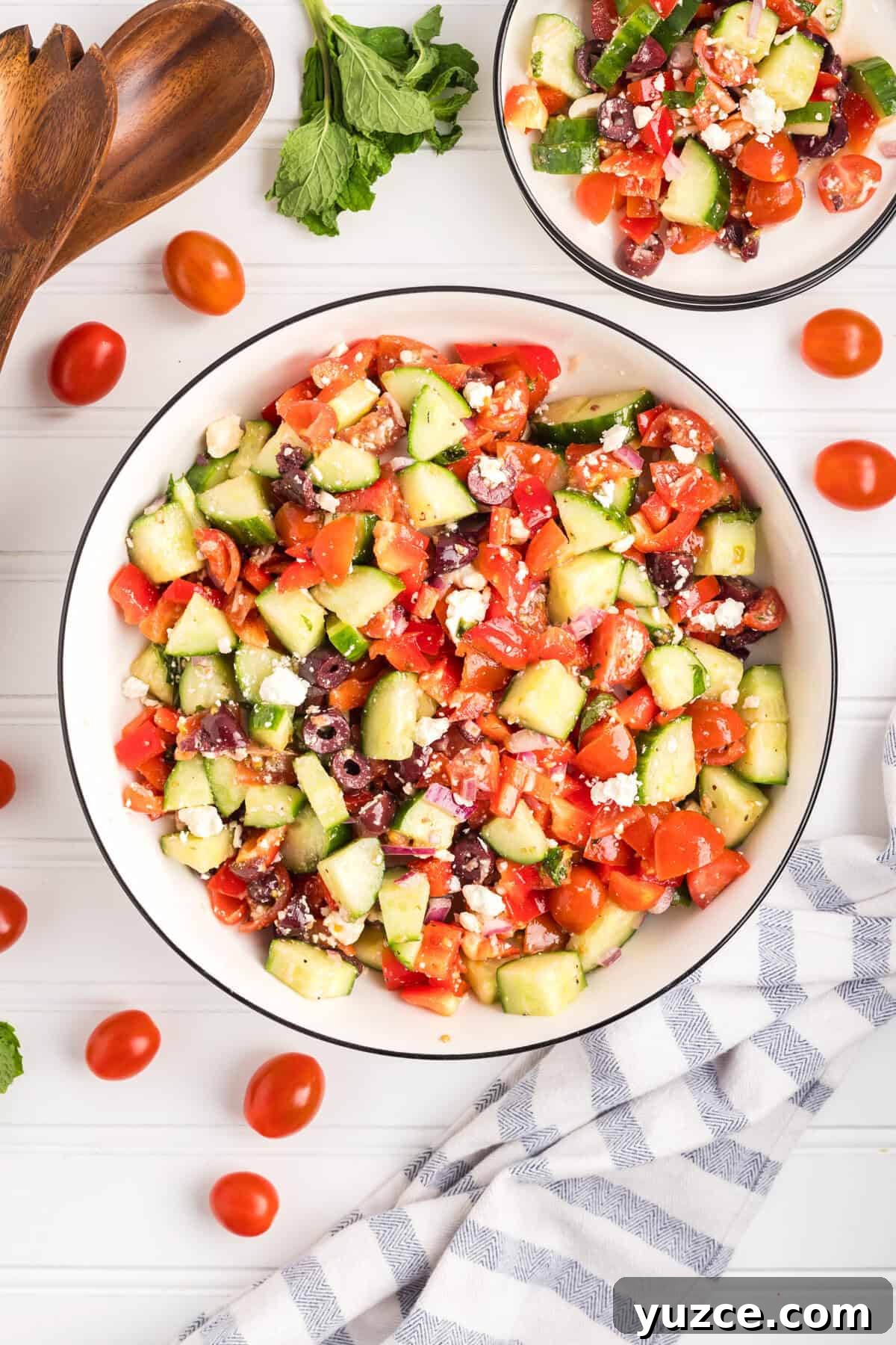 A top-down view of a large bowl of chopped Greek salad with a smaller serving bowl nearby.