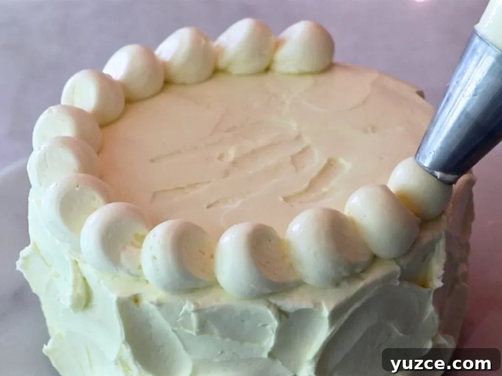 Luscious Lemon Buttercream Frosting Recipe for Cakes and Cupcakes 10 piping lemon buttercream on top of a cake