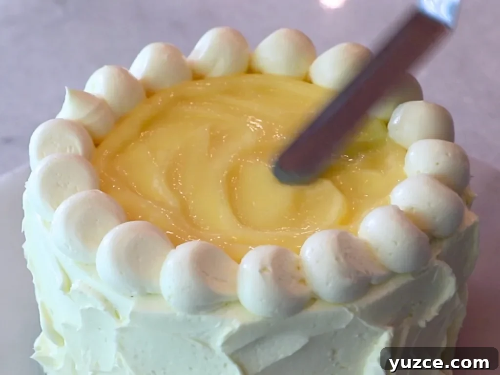 Luscious Lemon Buttercream Frosting Recipe for Cakes and Cupcakes 11 spreading lemon curd on top of a cake