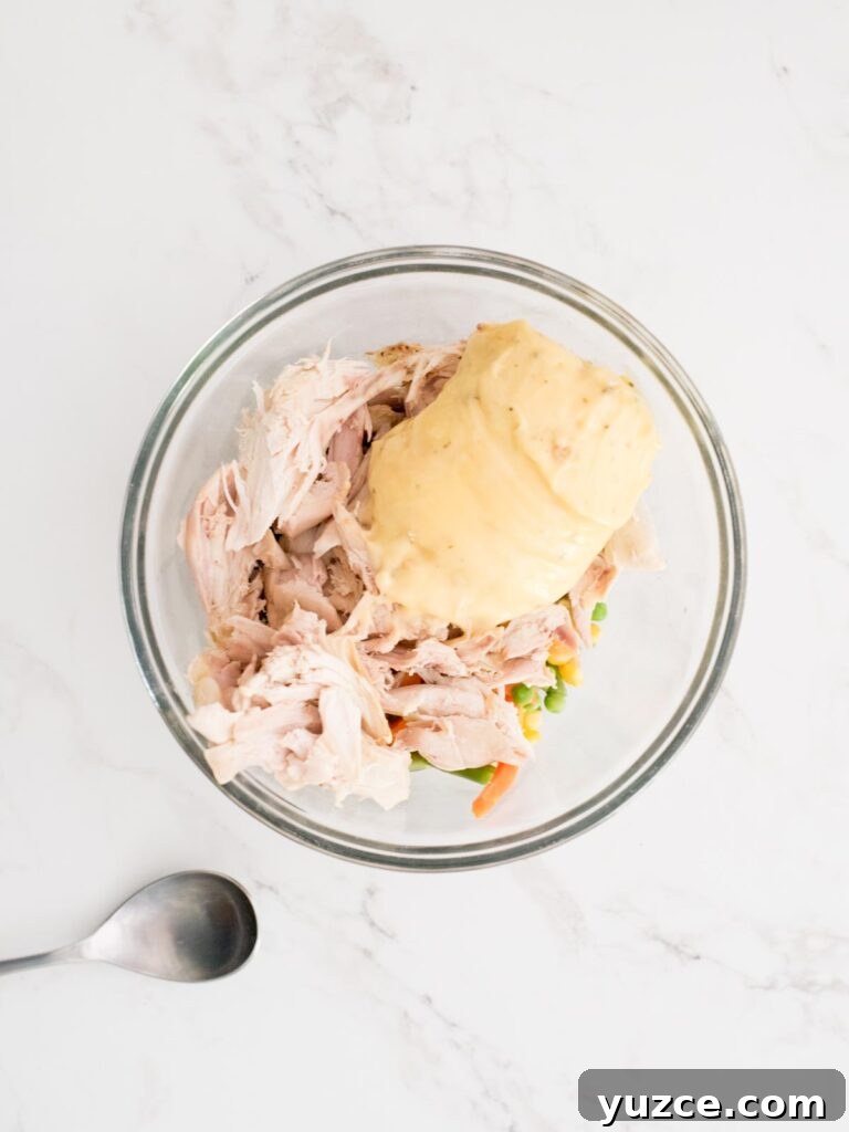 Mini Chicken Pot Pies Baked in Crescent Rolls 4 cream of chicken, vegetables, and chicken in a mixing bowl