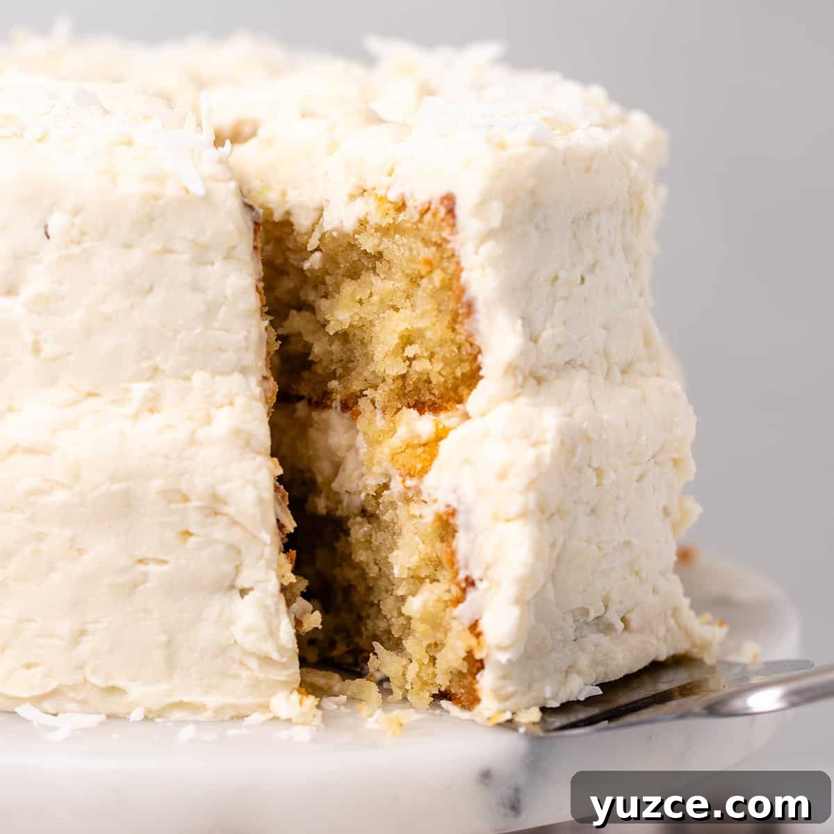 Moist Coconut Layer Cake Recipe 17 a slice of Coconut Cake being removed from the cake